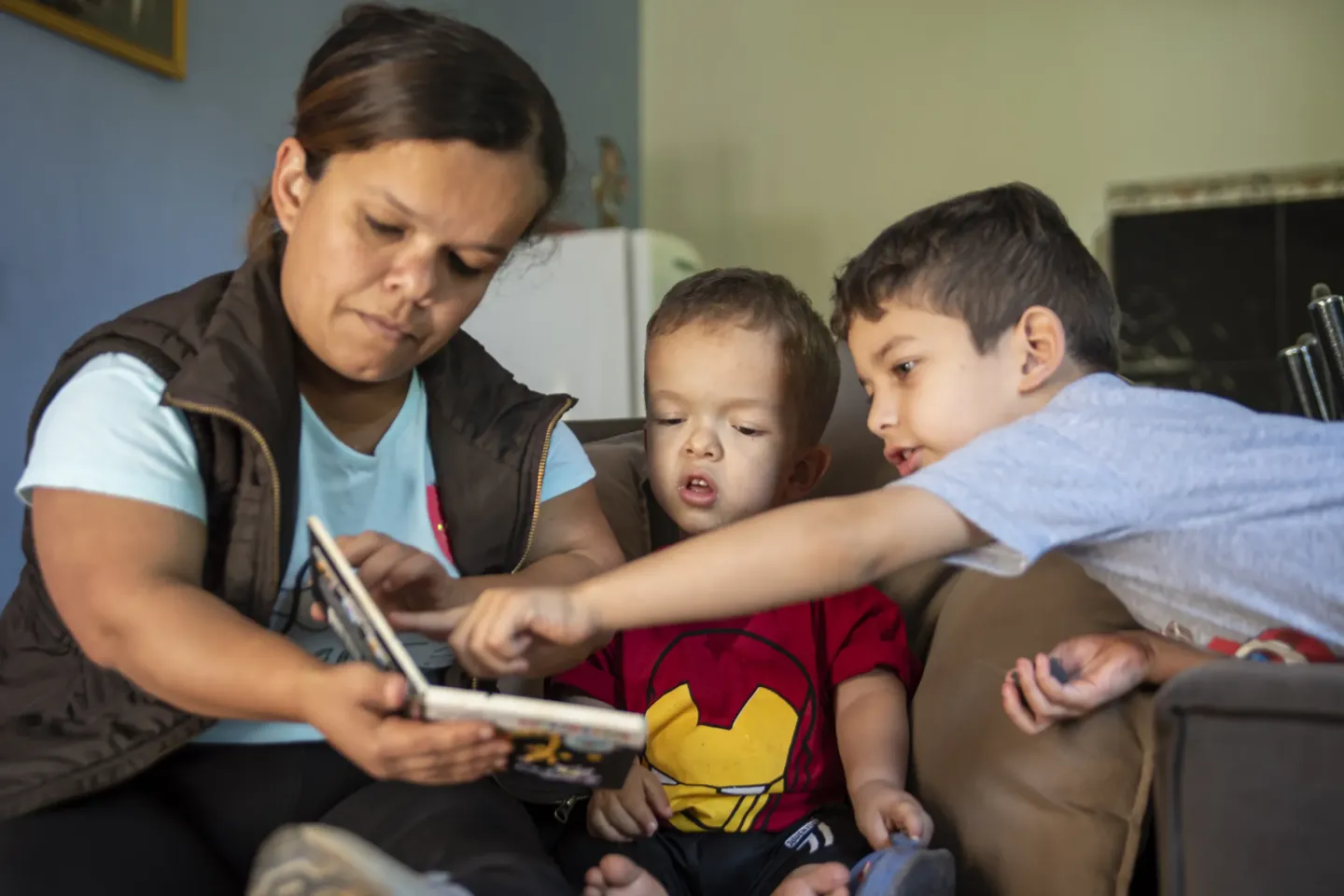 Una madre y dos ni&ntilde;os leyendo juntos un libro