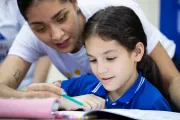 Ni&ntilde;a esta realizando una tarea con ayuda de su maestra