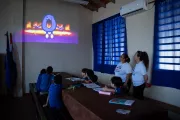 En el aula oscura, los ni&ntilde;os y ni&ntilde;as aprenden observando la proyecci&oacute;n de un video