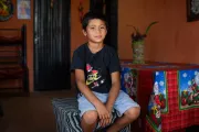 Un ni&ntilde;o sentado sobre un taburete sonriendo
