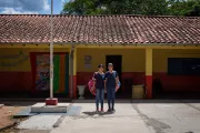 Dos ni&ntilde;as en el patio de la escuela posando con sus mochilas en el hombro
