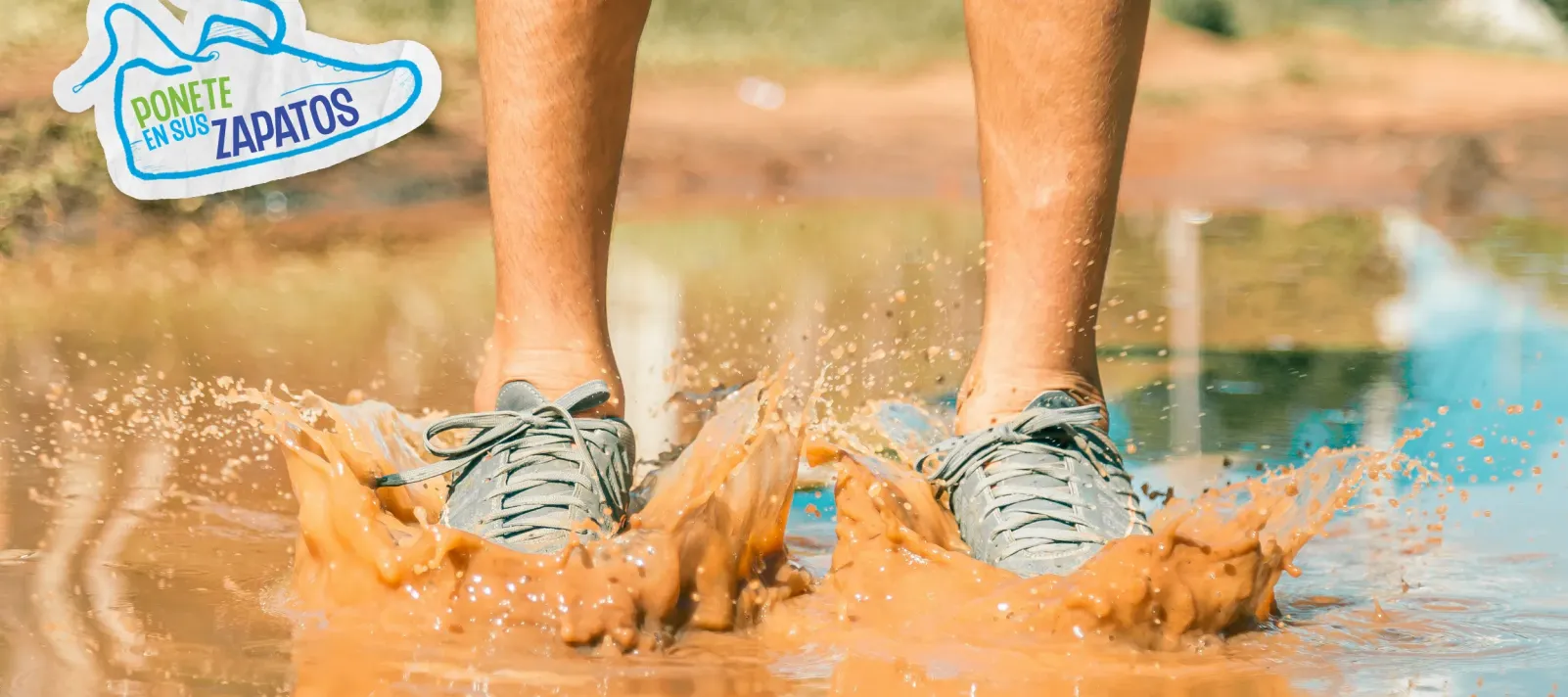 Los pies de un ni&ntilde;o con zapatos verdes pisando un charco