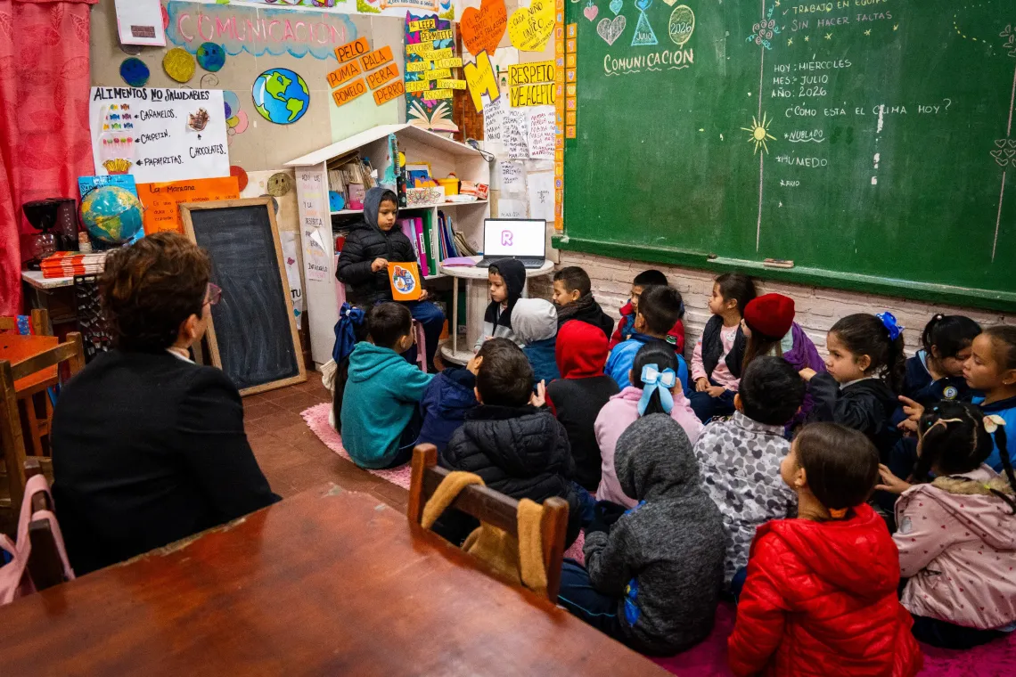 Estudiantes participan en una actividad grupal de aprendizaje en el aula, utilizando materiales educativos y recursos digitales.