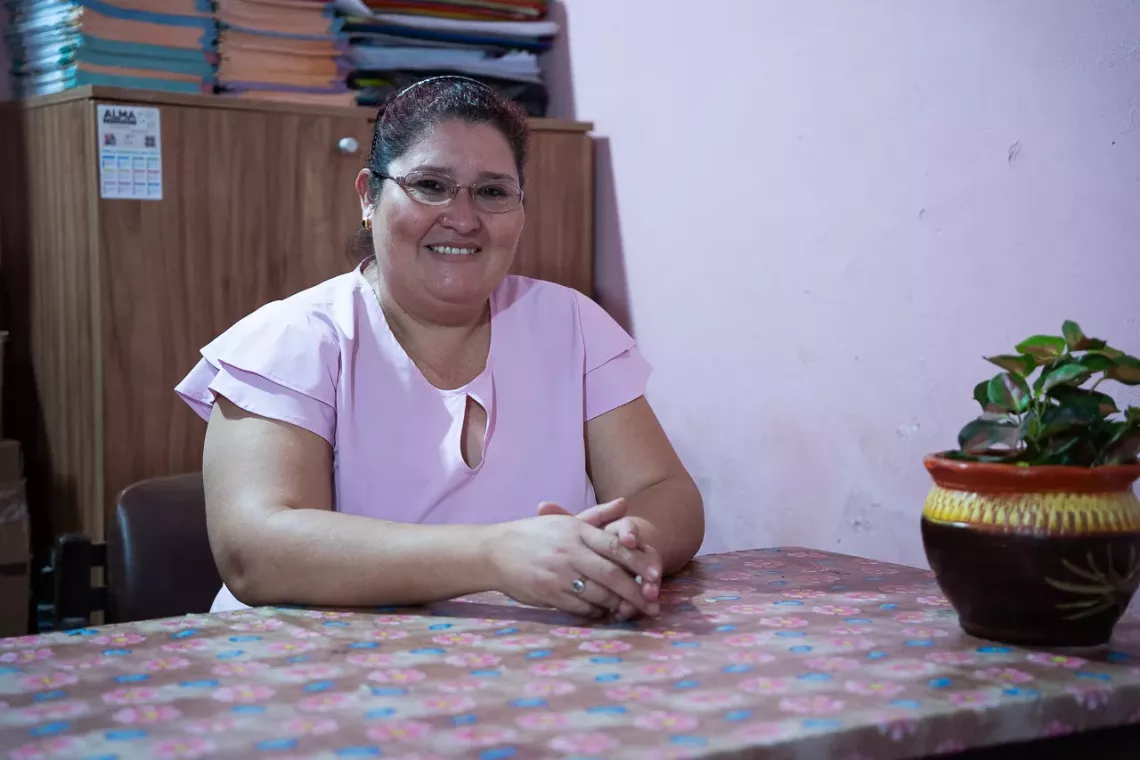 Mujer con remera rosa sentada en su oficina