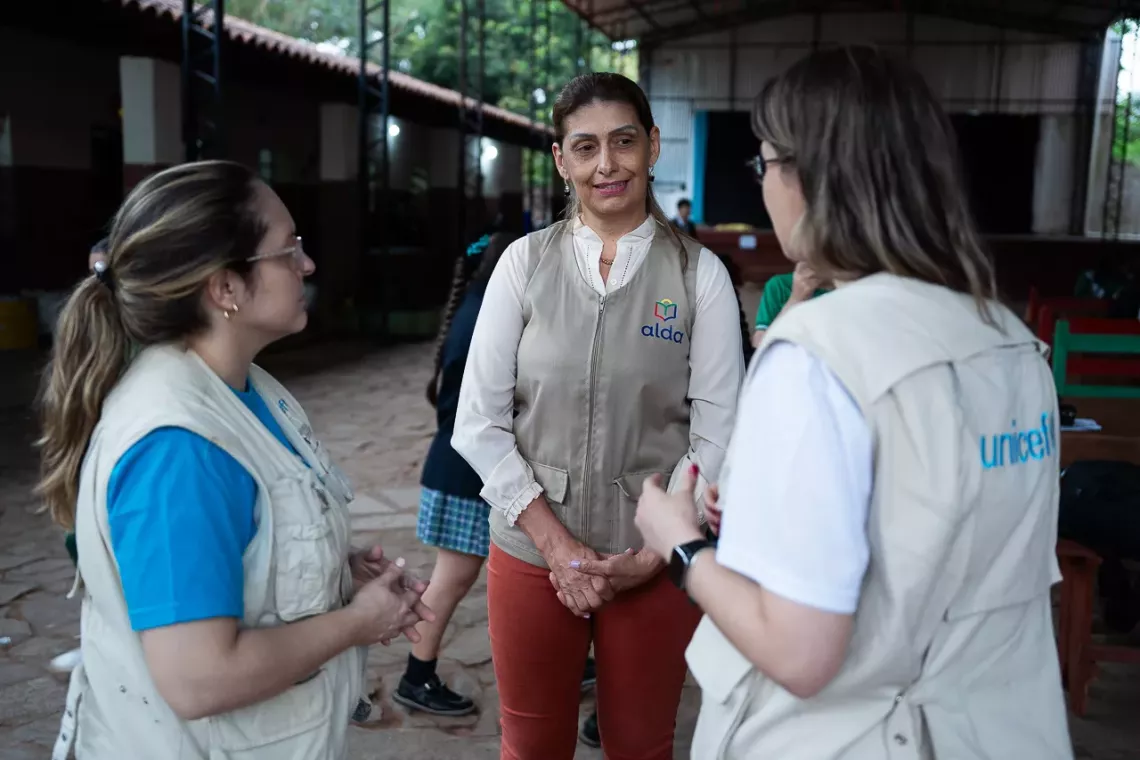 Tres mujeres conversan, dos de ellas tienen chaleos de UNICEF