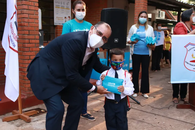 Rafael Obreg&oacute;n, representante de UNICEF entregando una cartuchera a un ni&ntilde;o en su primer d&iacute;a de clases. 
