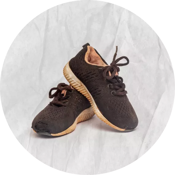 Zapatos negros con suelas blancas, se ven manchadas de tierra colorada