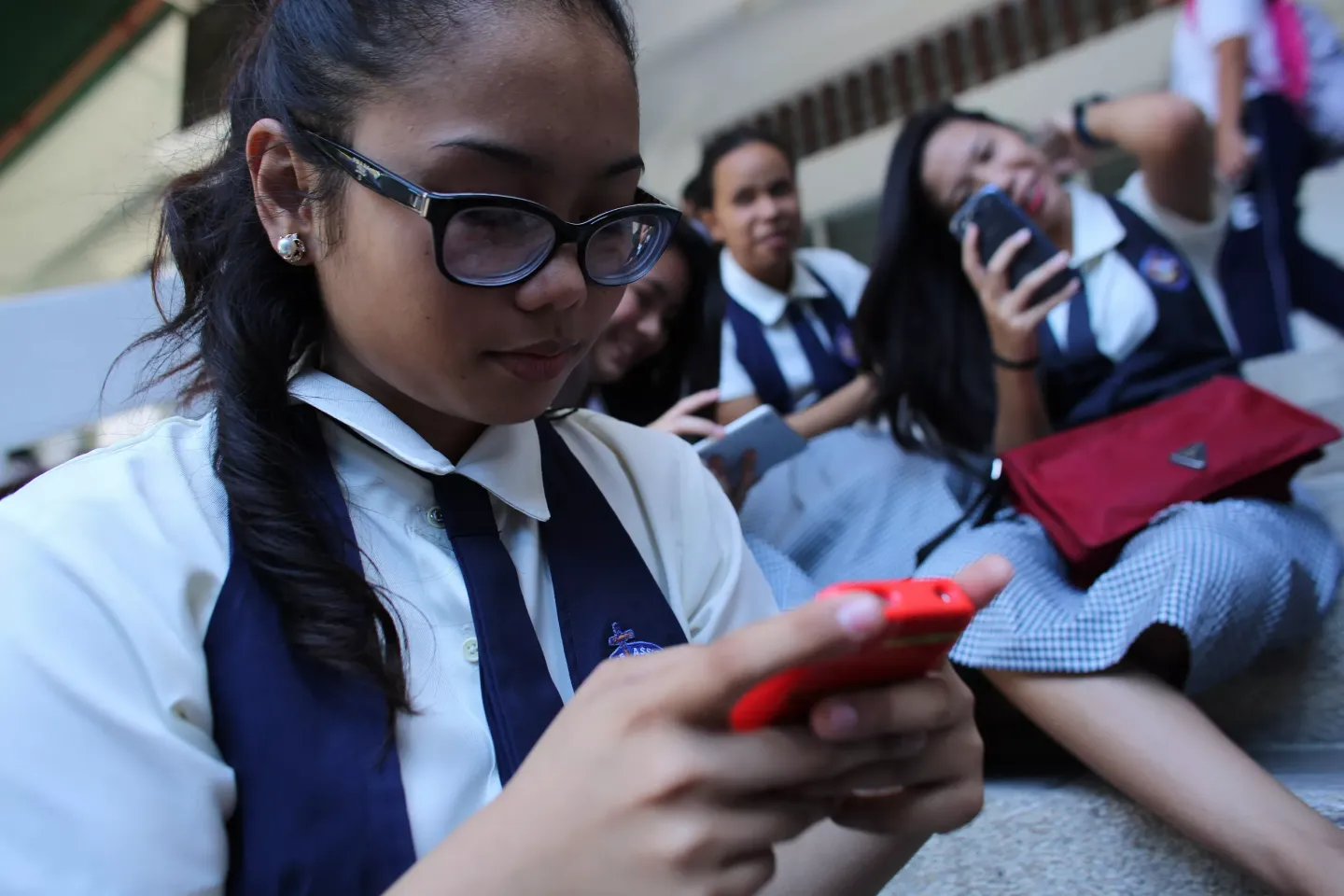 A student at St. Francis of Assisi School, and other girls, check their smart phones after classes in the Central Visayas city of Cebu, Philippines. 