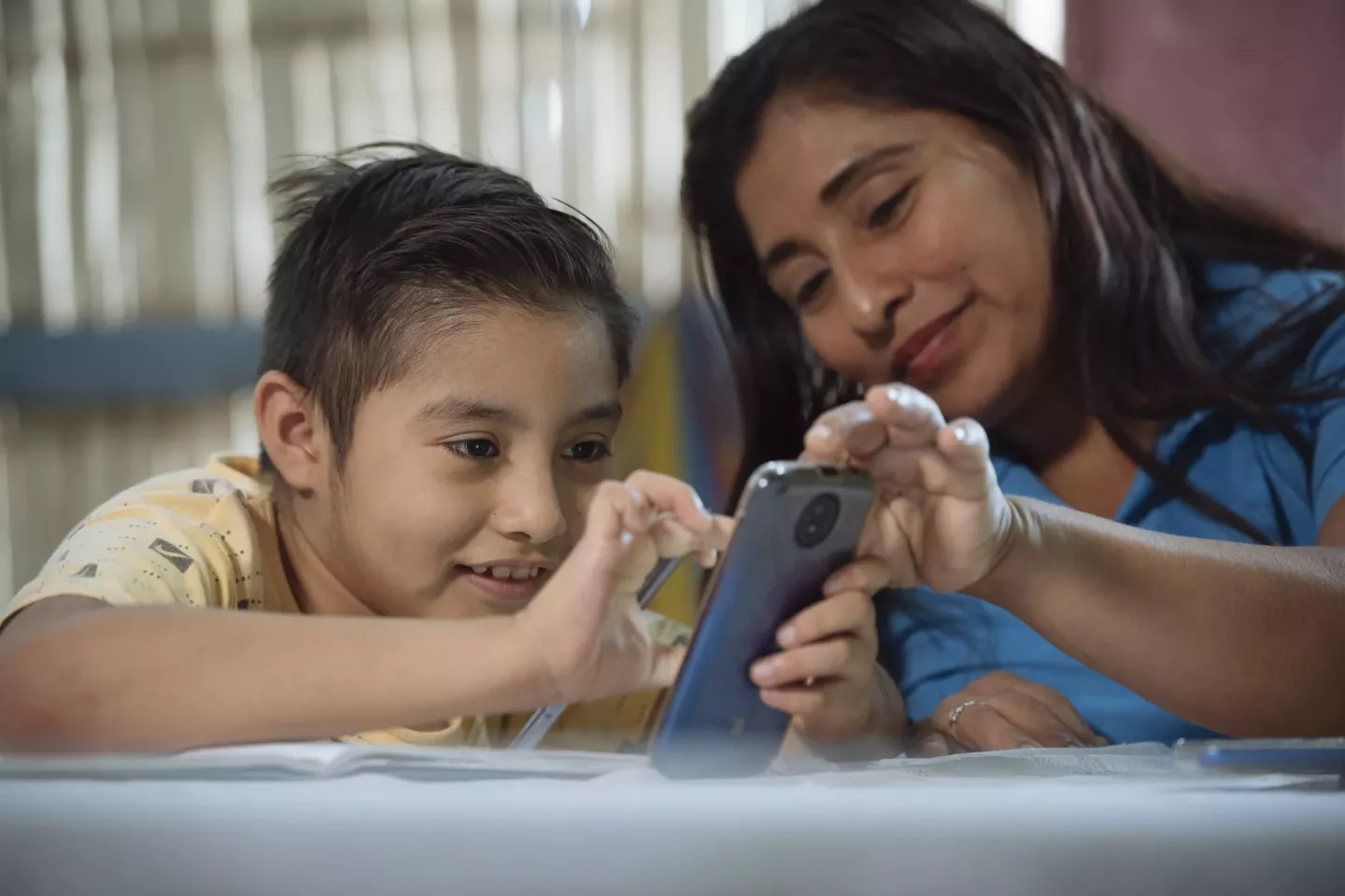 Un ni&ntilde;o y su madre en Ecuador miran un tel&eacute;fono m&oacute;vil