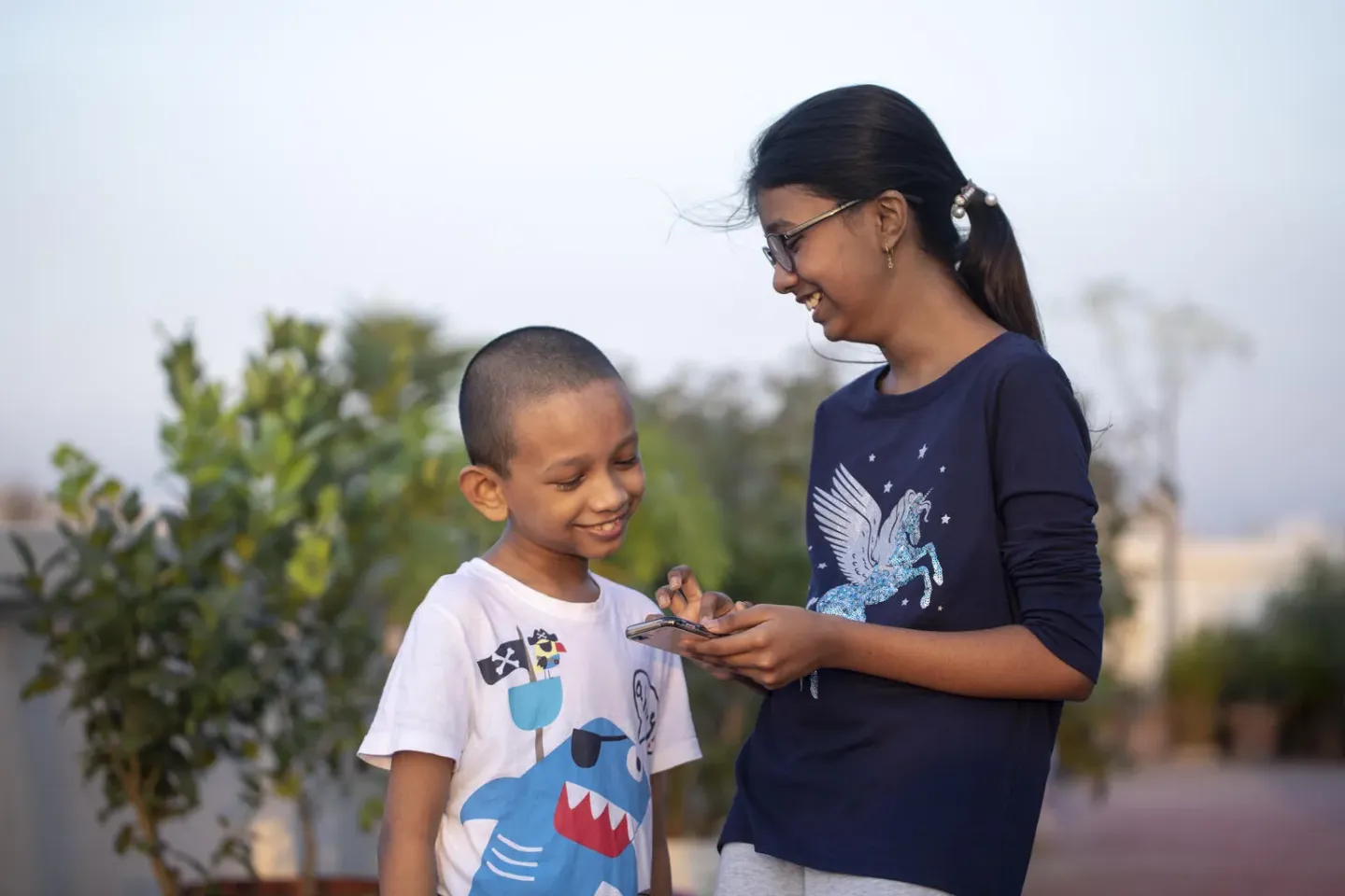 A girl shows her mobile phone to a younger boy in Bangladesh