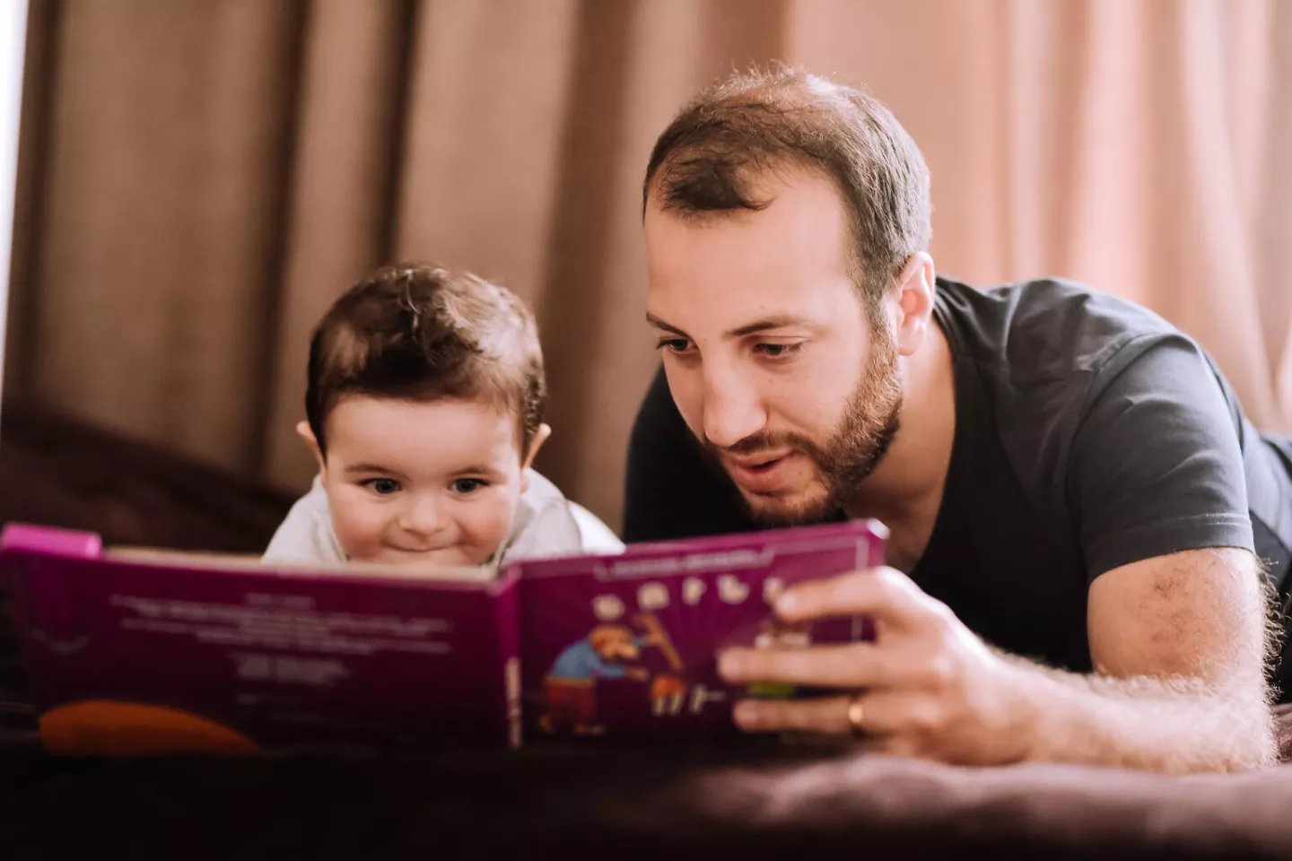 Un p&egrave;re, &agrave; droite, lit un livre &agrave; son enfant.  