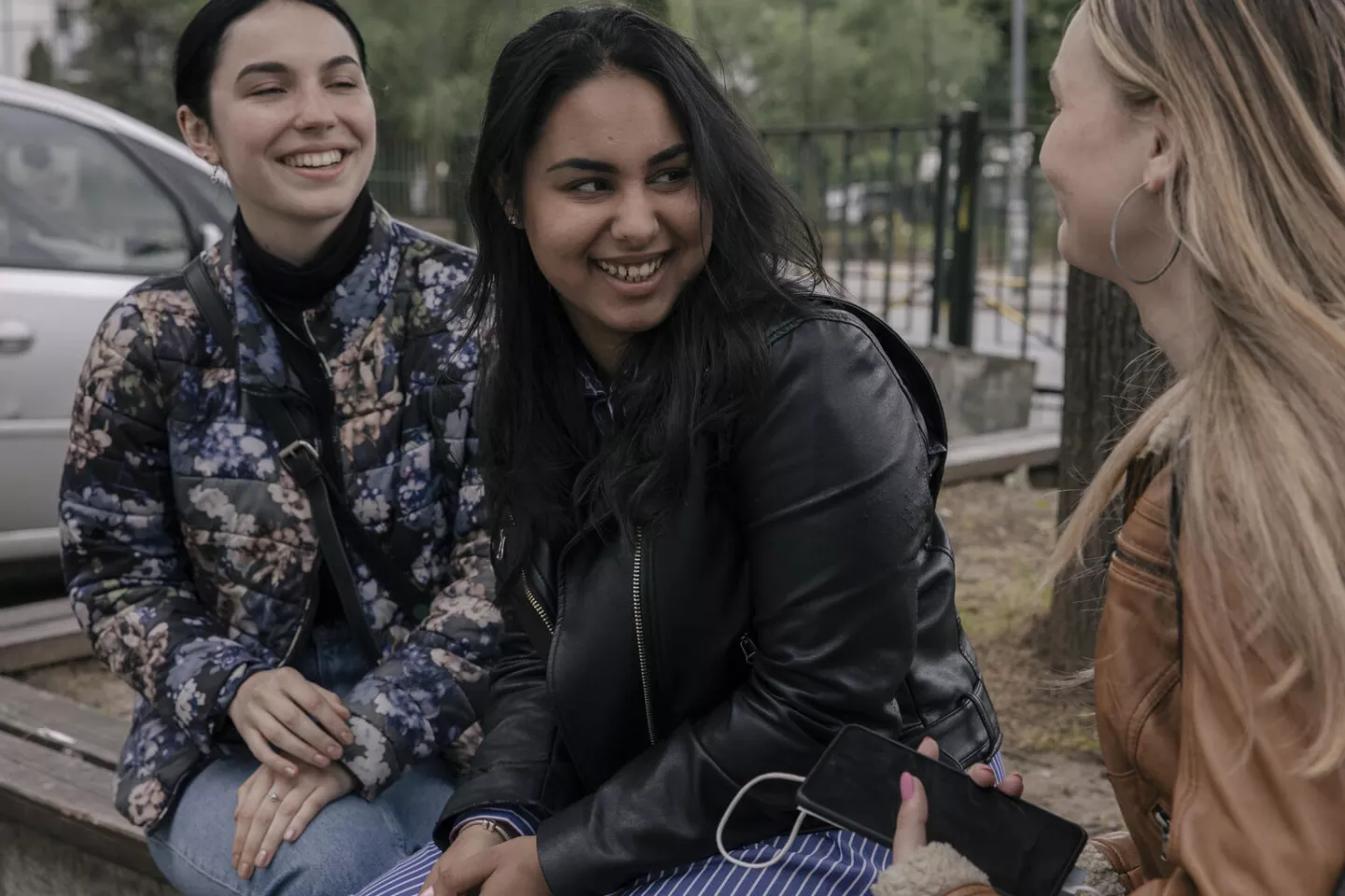 Trois jeunes filles sourient. Elle sont assises. 