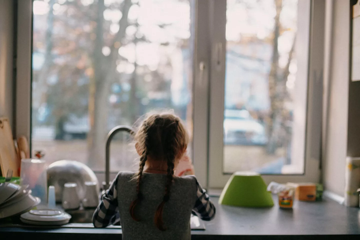 Une petite fille de dos regarde par la fen&ecirc;tre.