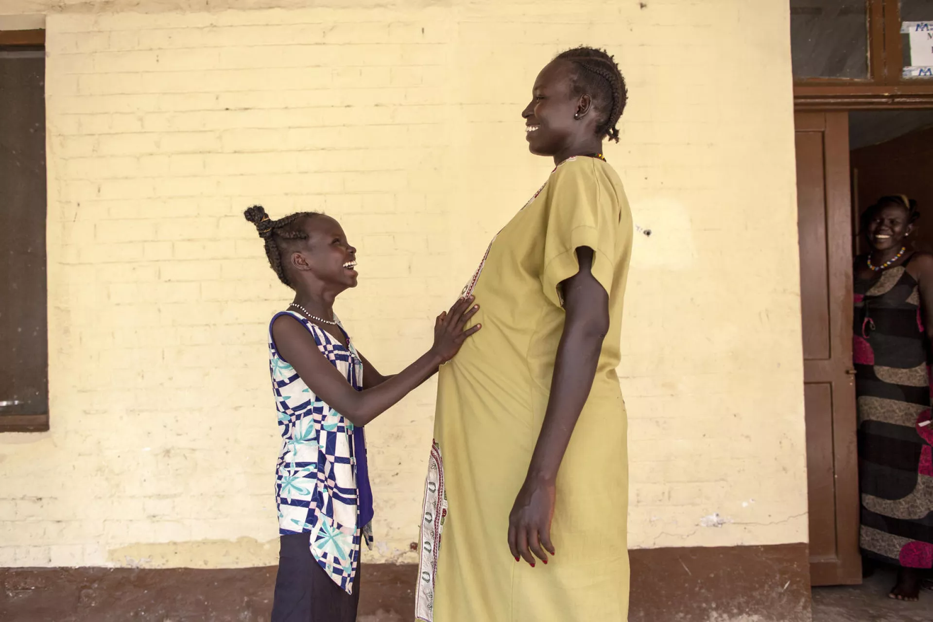 11 year old Nyanyiik Abile touches the stomach of Sundoay John - who is 9 months pregnant with her second child - outside the UNICEF-supported maternity ward at Malakal Teaching Hospital, South Sudan.