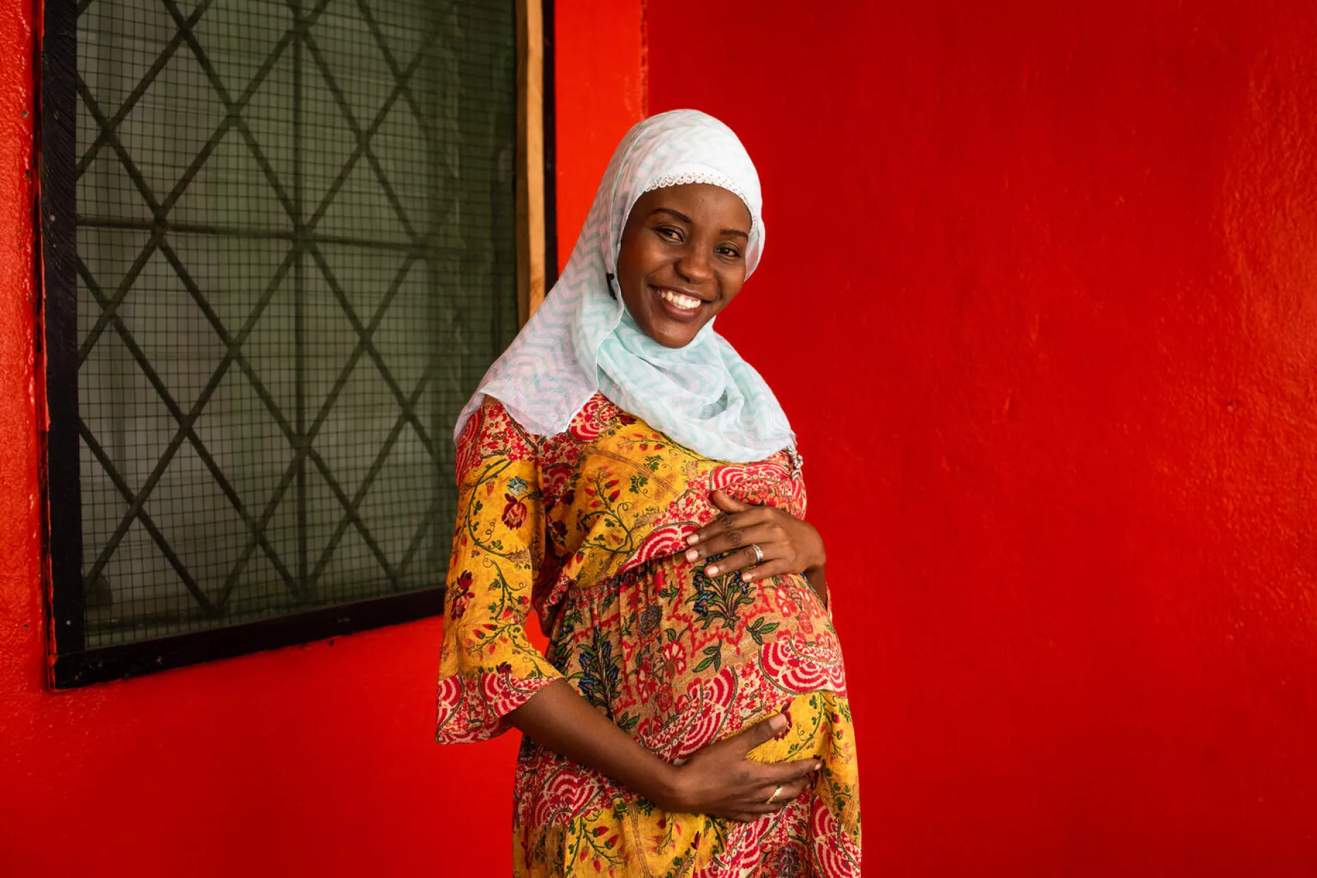 Ummu Paasewe, a mother of two and expecting a third child, stands for a portrait outside her home in Monrovia, Liberia.