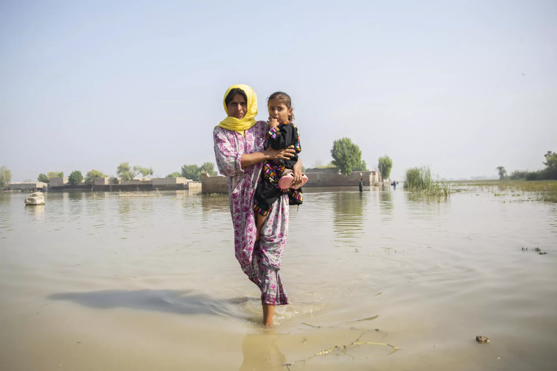 Une femme porte un enfant dans ses bras dans un endroit inondé 