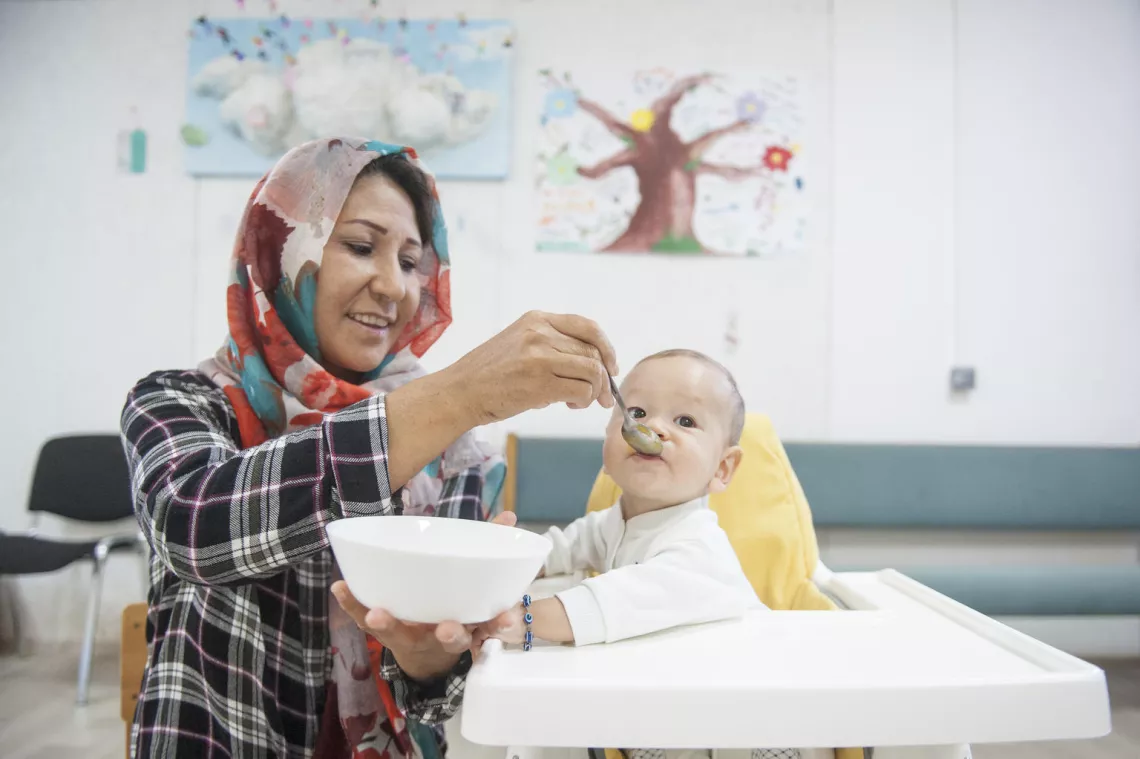 Refugee mother feeding her baby at ADRA community centre in Belgrade, Serbia.