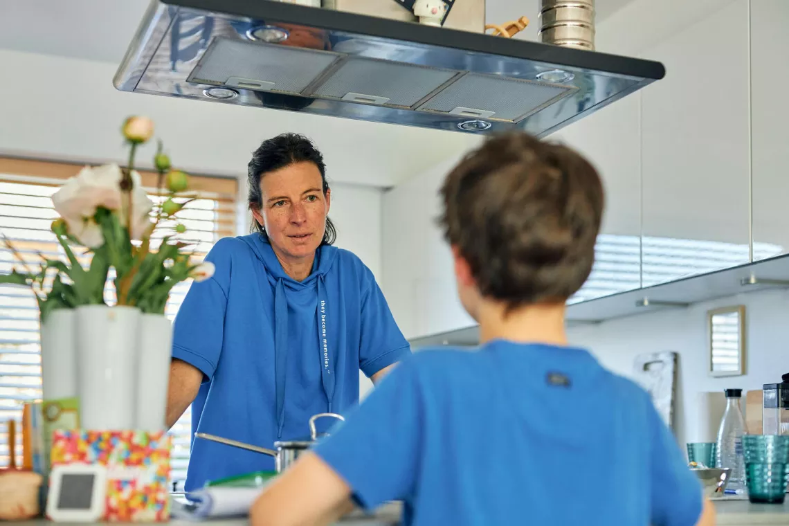 Une m&egrave;re se tient debout en face de son fils (de dos)
