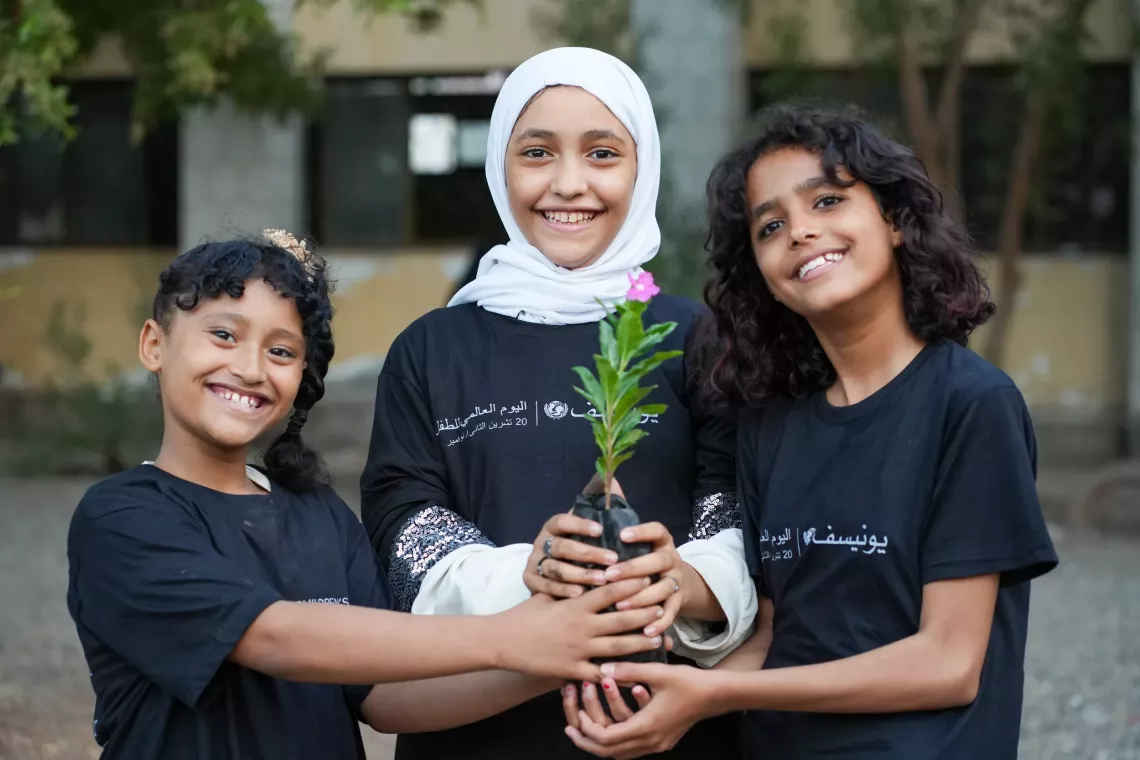 طلاب مدرسة يحملون شتلة معًا 