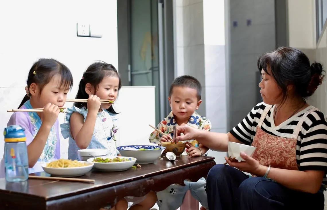 Zhang Qin and her grandchildren eat lunch at their family house in Guizhou Province, China.