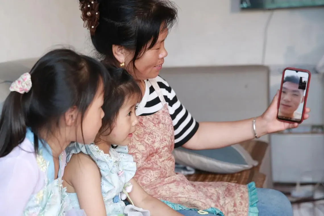 Zhang Qin and her two grandchildren make a video call with the girls' father at their family house in Guizhou Province, China.