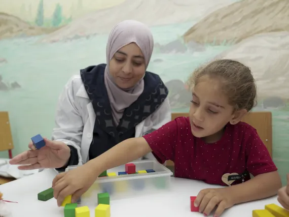 Sara, a specialised teacher at a UNICEF-supported self-learning centre for children with disabilities, helps Rahik, 5, through an educational game in Dar&rsquo;a city, Syria.