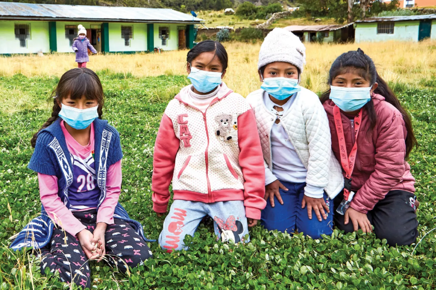 Un grupo de cuatro ninas sentadas frente a su escuela