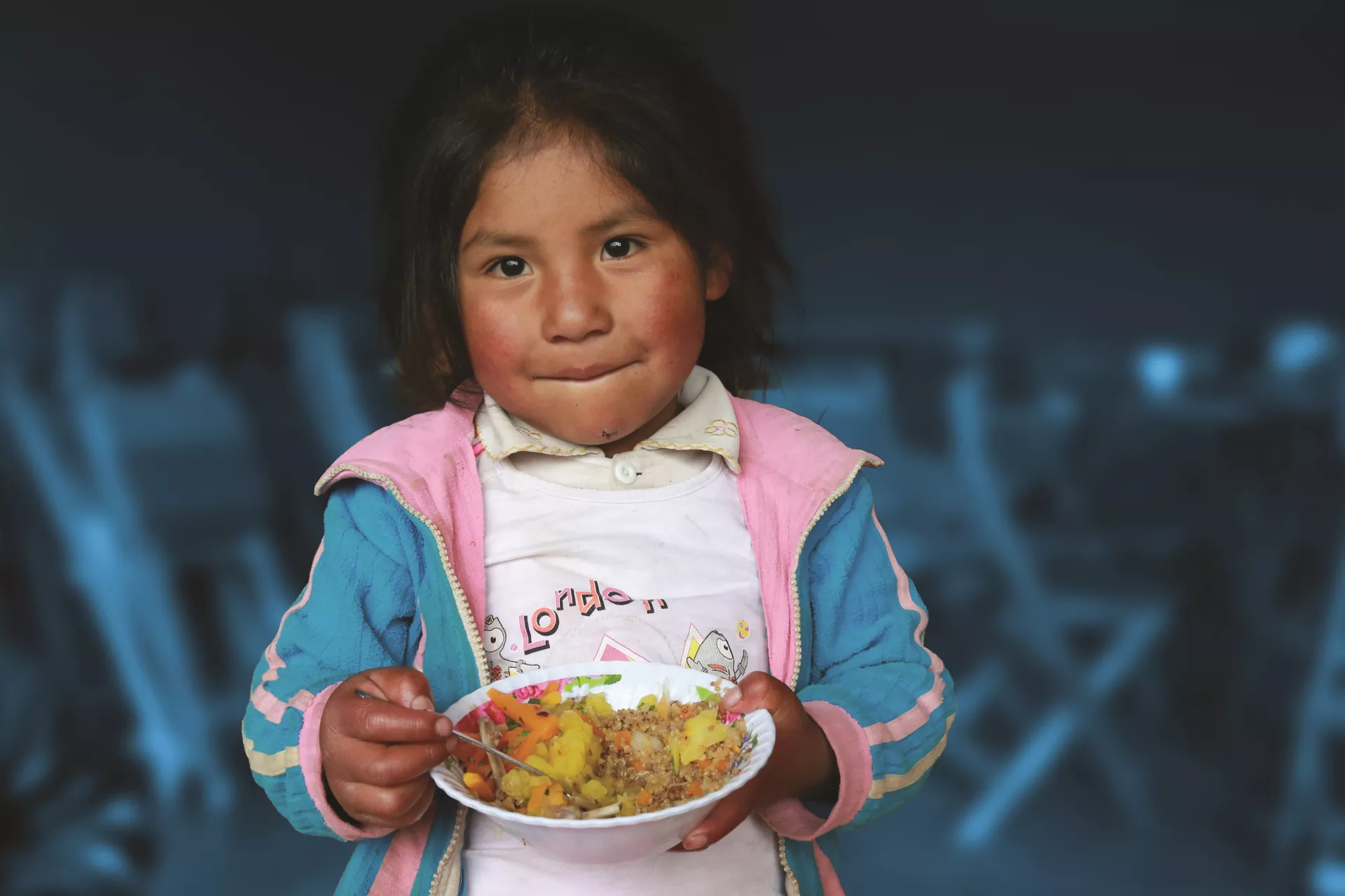 Una ni&ntilde;a sostiene un plato de comida, en Cusco