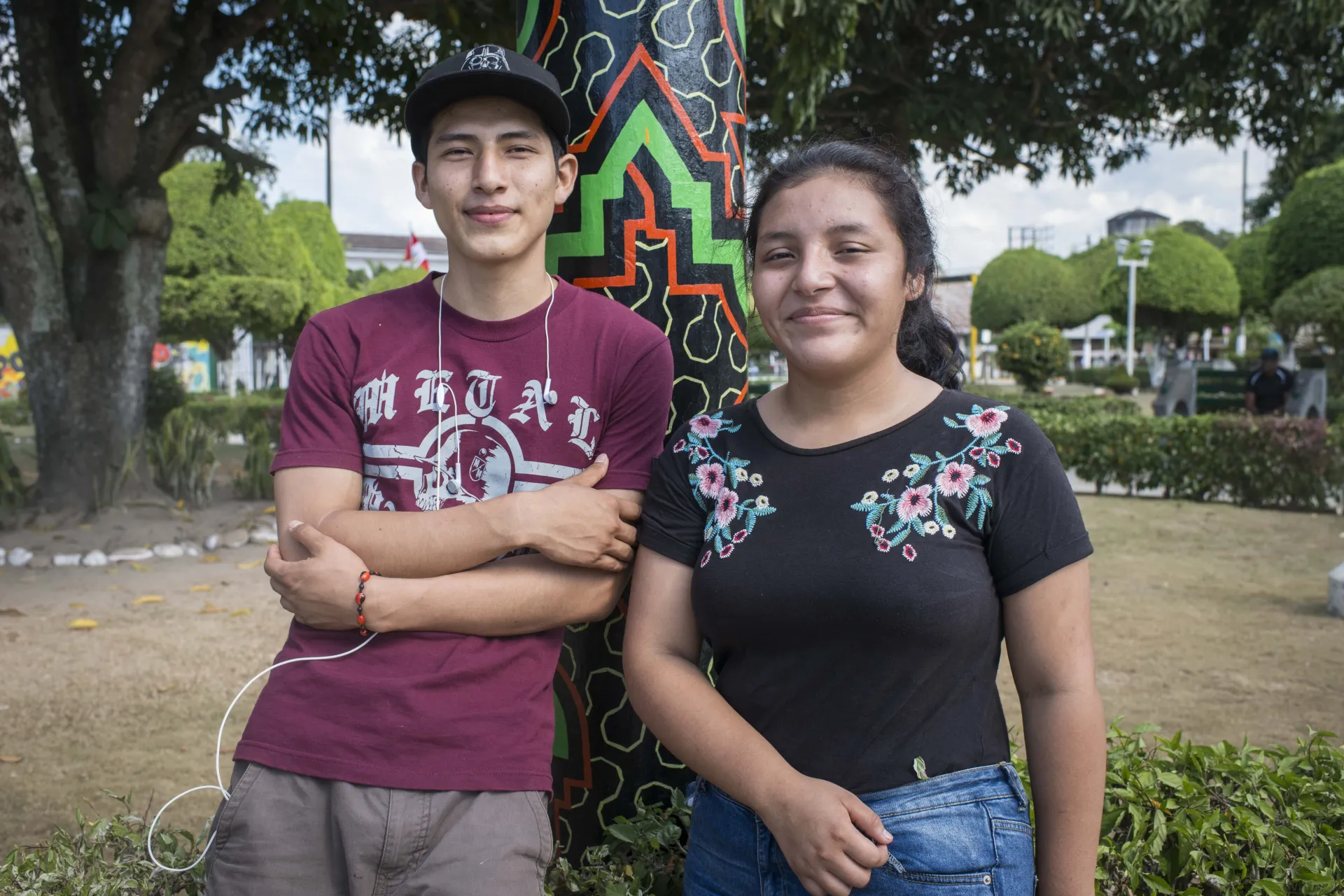 Dos adolescentes en un parque de Ucayali, parados frente a un poste.