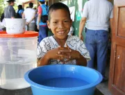 Niño vestido con traje típico lavándose las manos en una batea