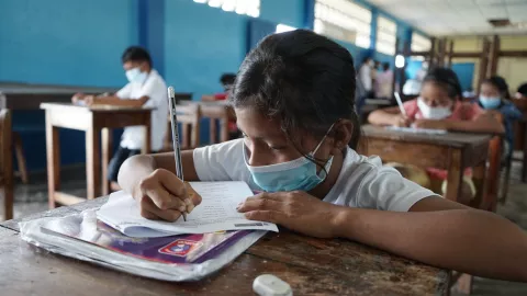 Una niña escribe en su cuaderno. Está en un aula de una comunidad amazónica