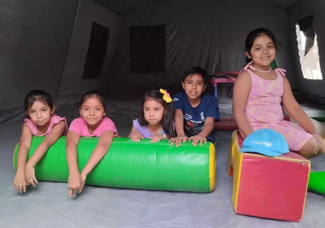 Ni&ntilde;as y ni&ntilde;os sentados y sonriendo, frente a juegos.