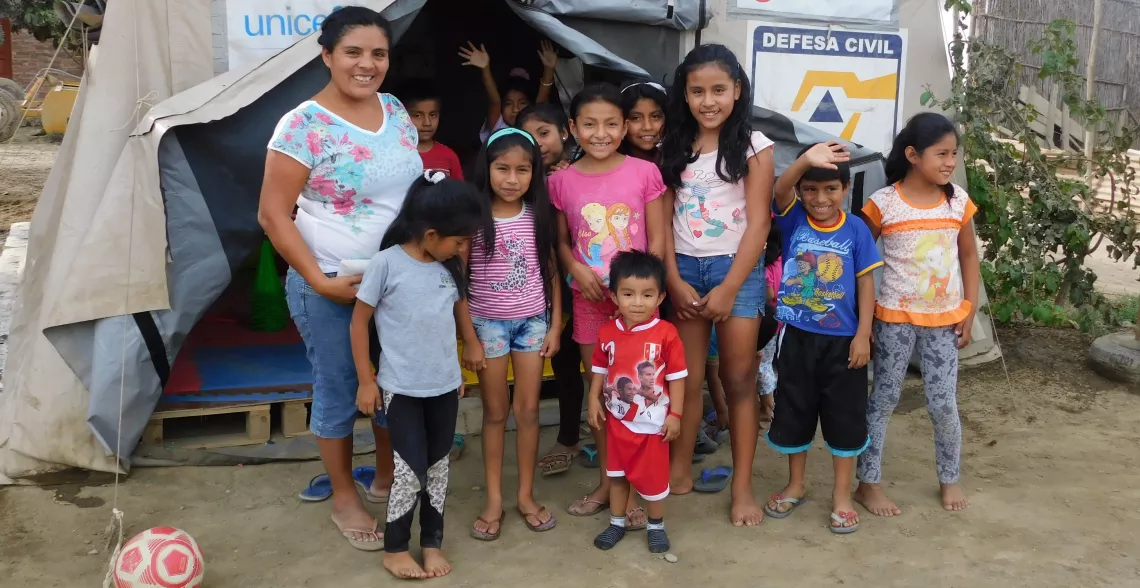 Un grupo de ninos y una mujer delante de una carpa
