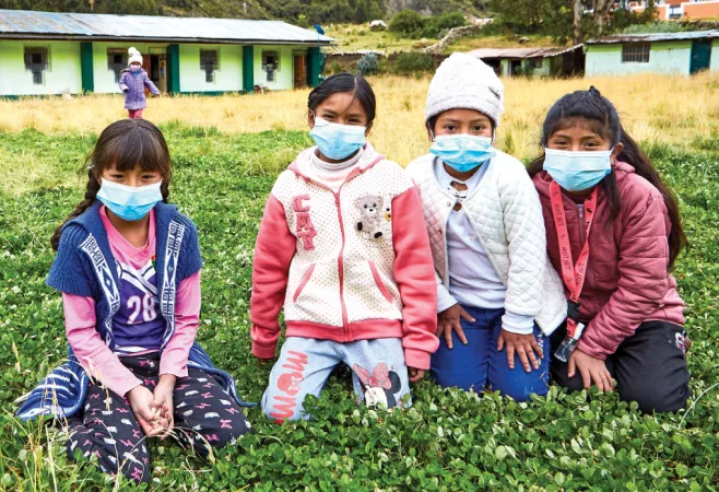 Un grupo de cuatro ninas sentadas frente a su escuela