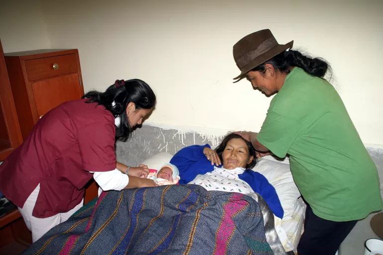 Una madre y su hijo reci&eacute;n nacido son atendidos por dos profesionales de la salud.