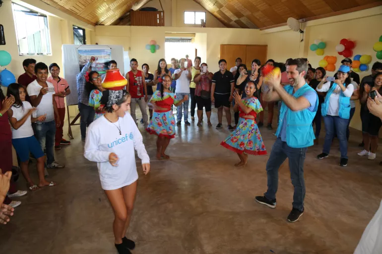 Isabela Moner y Marco Zunino bailando con ni&ntilde;as vestidas con trajes t&iacute;picos