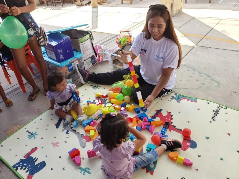 Una mujer jugando con dos ninos 
