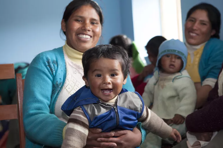 Ni&ntilde;o sonriendo en las piernas de su madre
