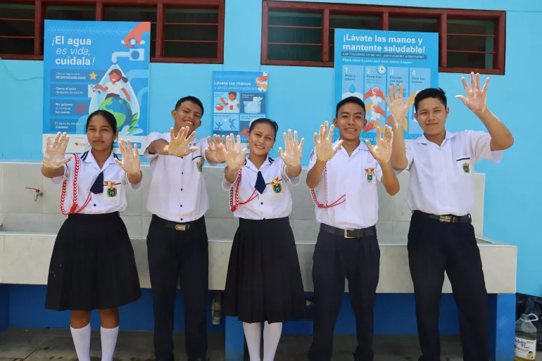 Adolescentes en su escuela muestran sus manos recien lavadas