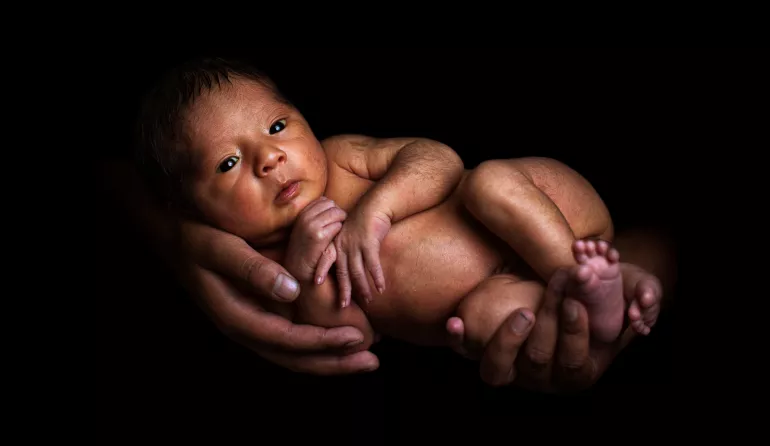 Un beb&eacute; es sostenido en las manos de su madre