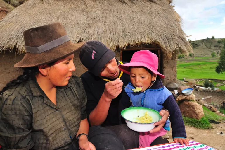 Madre y padre alimentan a una ni&ntilde;a en un entorno andino
