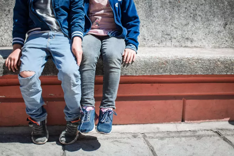 Dos ni&ntilde;os sentados en una banca