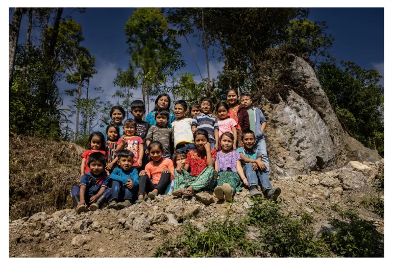 A group of children between 5 and 13 years of age pose smiling in front of the camera in Alta Verapaz, Guatemala.