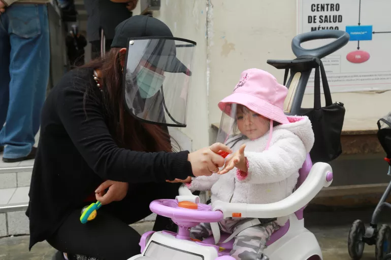 Una madre desinfecta las manos de su hija para prevenir el contagio de la COVID-19