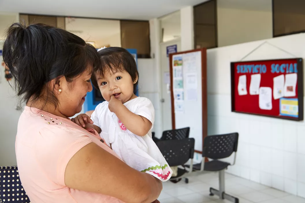 Una madre sostiene a su hiza en brazos en un centro de salud. Carabayllo