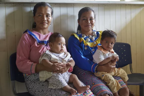 Dos madres esperan sentadas con sus bebes sobre sus piernas