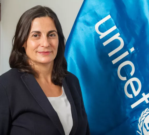 Ana de Mendoza, Representante, frente a una bandera de UNICEF