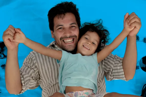 Un padre y su hija sonr&iacute;en mientras juegan.