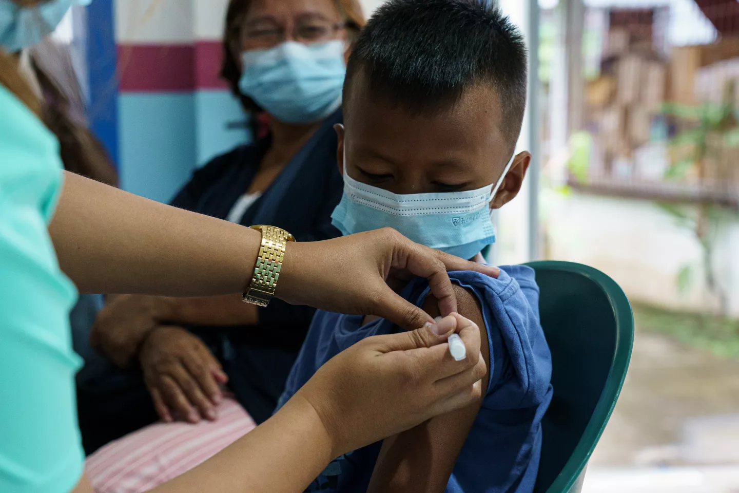 A child wearing a face mask receives a dose of the COVID-19 vaccine