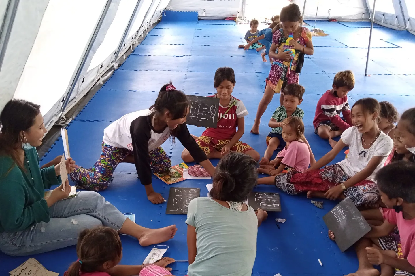 A volunteer teacher conducts a learning session inside a UNICEF tent